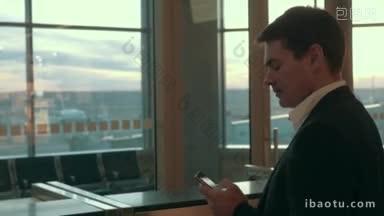 年轻认真的商人在机场用智能手机打短信，看着窗外